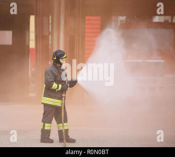 Italia, Italy - May 10, 2018: italian fireman with uniform and helmet uses the hydrant at fire station Stock Photo