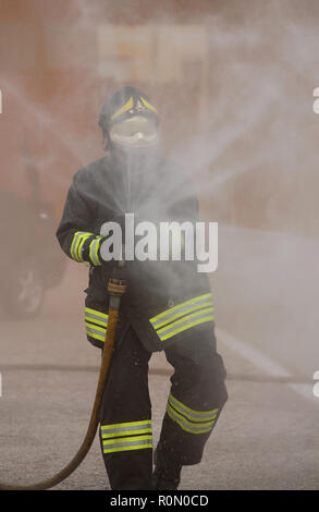 Italia, Italy - May 10, 2018: italian fireman with uniform and helmet uses the hydrant with foam during an exercise in the fire department Stock Photo