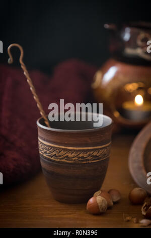 Dark background with a hot drink in a ceramic Cup and the scattered nuts hazelnuts on a wooden surface. Stock Photo