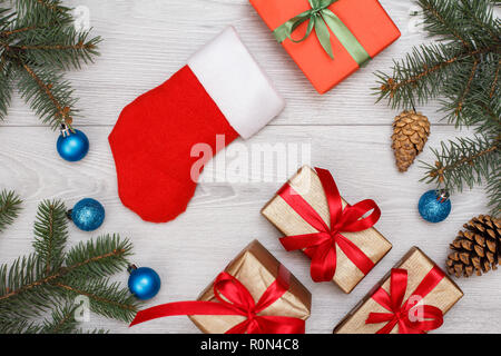 Christmas decoration. Santa's boot, gift box, fir tree branches with cones and christmas toys on gray wooden boards. Top view. Christmas greeting card Stock Photo