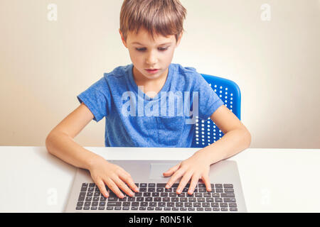 Concentrated boy typing on laptop computer Stock Photo
