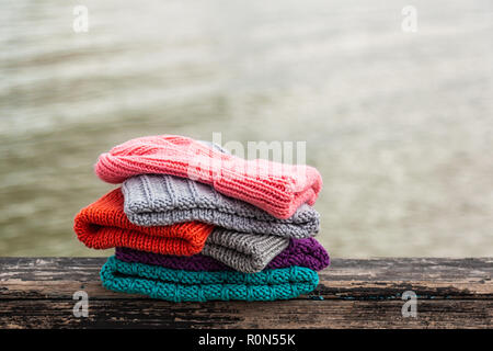 Beautiful background knitting winter blue and pink, red a lot hat. Crochet hook handmade. Close-up of knitted hats of blue, yellow, pink and gray Stock Photo