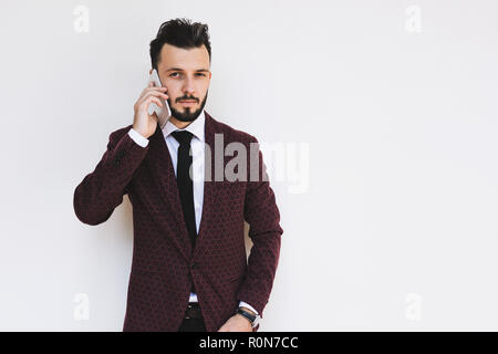 Trendy and fashionable businessman posing on a white background and talking on the phone. Stock Photo