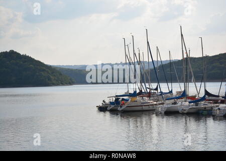 Boats in the Ruhrsee (Germany) on bright daylight before green forests mounds Stock Photo