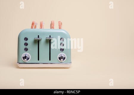 Retro green four slice double toaster with finished toast on a vintage tan background with copy space and room for text Stock Photo