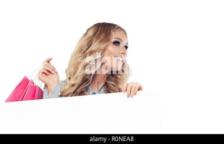 Perfect smiling woman with shopping bags and white empty paper signboard banner isolated on white background Stock Photo