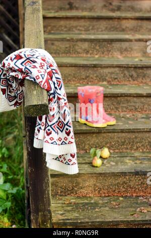 Autumn fruits on a vintage old wooden staircase. Autumn mood, warm clothes. Life style. Porch of the old house. Red  Rubber boots. Stock Photo