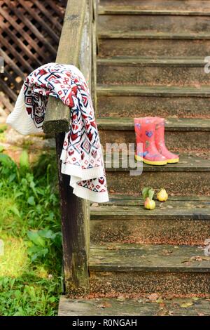 Autumn fruits on a vintage old wooden staircase. Autumn mood, warm clothes. Life style. Porch of the old house. Red  Rubber boots. Stock Photo
