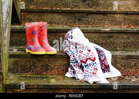 Autumn fruits on a vintage old wooden staircase. Autumn mood, warm clothes. Life style. Porch of the old house. Red  Rubber boots. Stock Photo