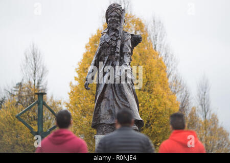 Three men take a moment to look at the Lions of the Great War monument in Smethwick, West Midlands. The 10-foot high bronze figure of a Sikh soldier is the UK's first statue of a World War soldier from South Asia, and commemorates 100 years since the end of the war. Stock Photo