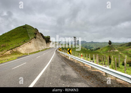An asphalt road running through green countryside on an overcast day Stock Photo