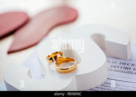 Two broken wedding rings on wooden paragraph. Divorce, separation and family law concept Stock Photo