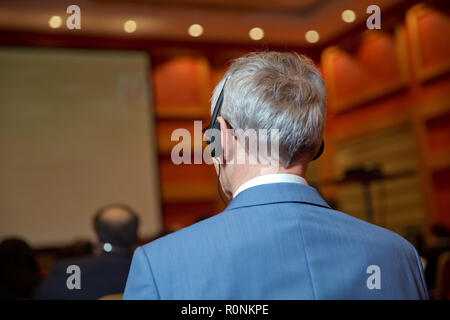 bald security guard with the headset to control people . heated debate at a conference discussion Stock Photo