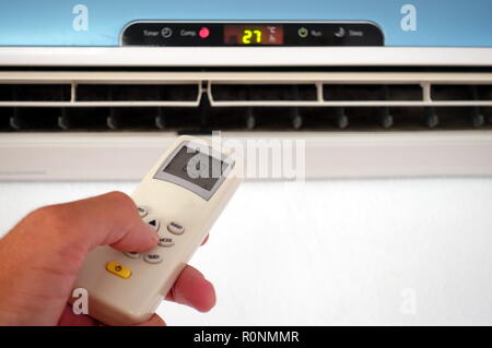 Someone changing the settings of a domestic AC or Air Conditioning unit with a remote control - focus on the remote Stock Photo