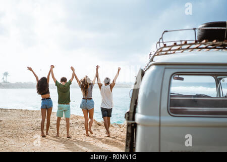 Happy friends walking at beach and rise up hands Stock Photo
