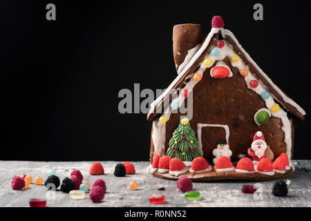 closeup of a homemade gingerbread house on a gray rustic wooden table, against a black background with some blank space Stock Photo