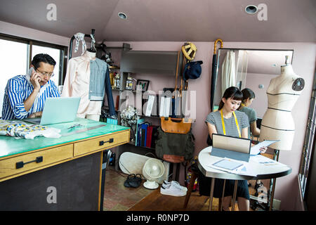 Japanese male and female fashion designers working in a studio. Stock Photo