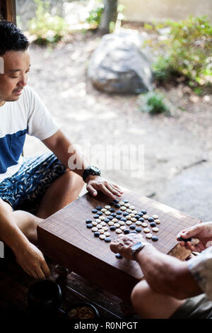 High angle view of two Japanese men sitting on floor, playing Go. Stock Photo