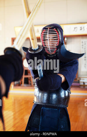 Two Japanese Kendo fighters wearing Kendo masks practicing with wood sword in gym. Stock Photo