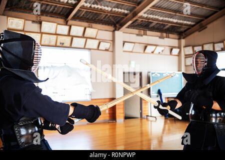 Two Japanese Kendo fighters wearing Kendo masks practicing with wood sword in gym. Stock Photo