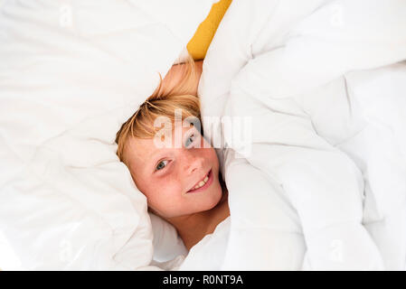 Overhead view of a smiling boy lying in bed Stock Photo