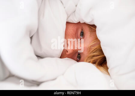 Portrait of a boy wrapped in a duvet Stock Photo