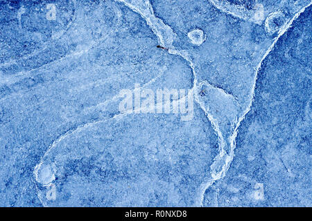 Abstract shot of the patterns created in a frozen puddle, the ice having partially thawed and refrozen several times. Stock Photo