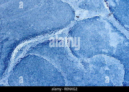 Abstract shot of the patterns created in a frozen puddle, the ice having partially thawed and refrozen several times. Stock Photo
