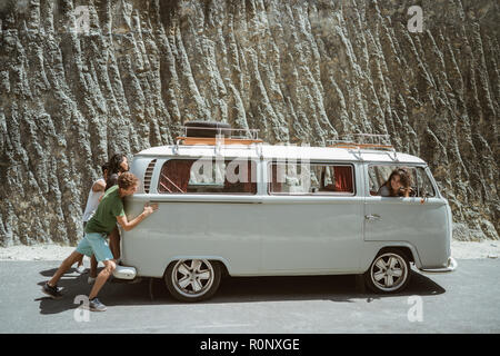 young people push broke down retro van Stock Photo