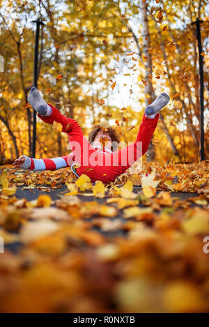 Boy jumping on a trampoline covered in autumn leaves, United States