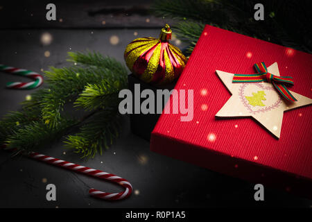 Fir branches on concrete gray background with red gift box and decorations. Christmas and New Year. Flat lay. Stock Photo