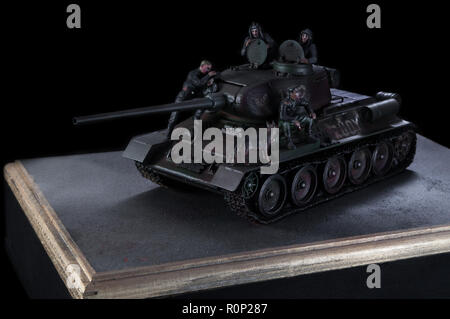 Model of the Russian battle tank T-34 fighting vehicle, with three soldiers nearby. Black background Stock Photo