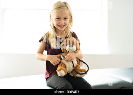 A doctor girl playing and cure bear at the pediatric Stock Photo