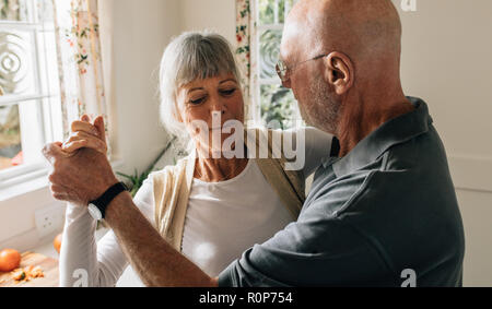 Senior couple dancing holding hands at home. Close up of an old man and woman having fun dancing at home. Stock Photo