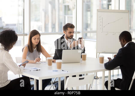 Diverse employees sitting at table using smartphones Stock Photo