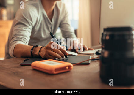 Close up of male designer working on graphics tablet using a stylus to edit photos. Artist using new technology for editing his artwork. Stock Photo