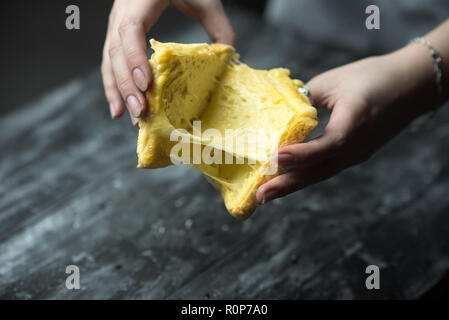 baked toast with stretched cheese in the hands of a woman Stock Photo