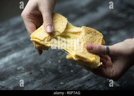 baked toast with stretched cheese in the hands of a woman Stock Photo