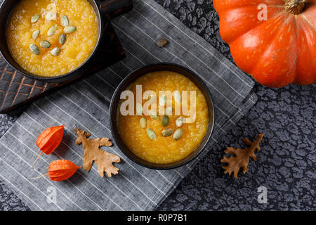Beautiful autumn still life for a postcard or a book with recipes. Pumpkin cream soup and fresh pumpkin. Top view. Stock Photo