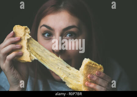 baked toast with stretched cheese in the hands of a woman Stock Photo