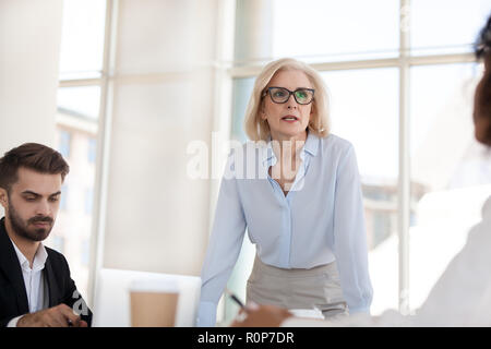 Serious mature businesswoman talk having discussion during brief Stock Photo