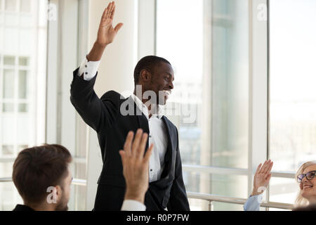 Black male coach hold teambuilding activity with workers raising Stock Photo