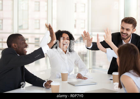 Excited diverse employees give high five at team meeting Stock Photo