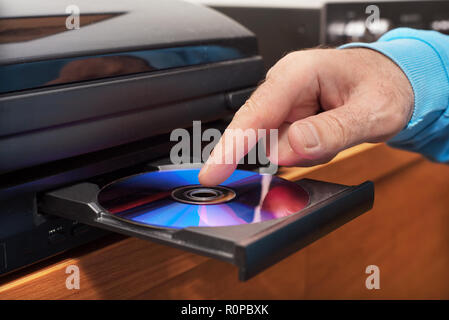 Hand holding DVD inserting to video player Stock Photo