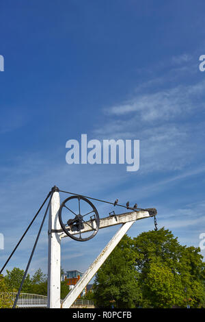 An old narrow boat crane made from wood painted white with a blue sky background Stock Photo