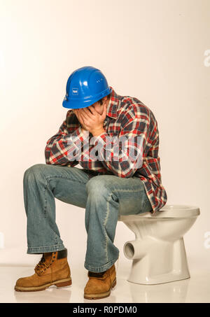 Depressed builder, sitting on an uninstalled toilet Stock Photo