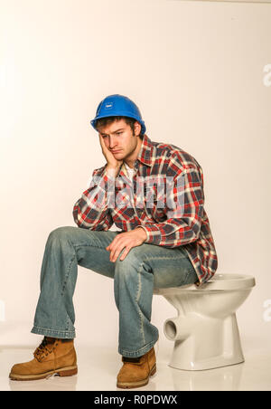 Depressed builder, sitting on an uninstalled toilet Stock Photo