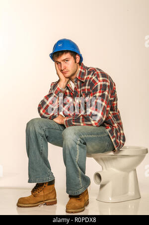 Depressed builder, sitting on an uninstalled toilet Stock Photo
