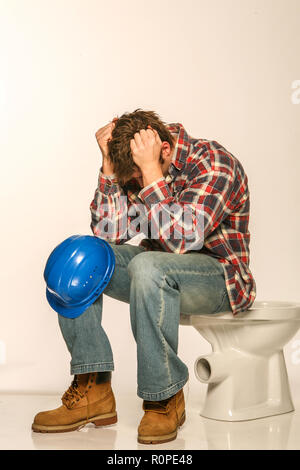 Depressed builder, sitting on an uninstalled toilet Stock Photo