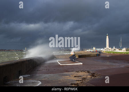 Waves breaking over the sea wall at southsea during a storm, war memorial and Spinnaker tower in the background Stock Photo